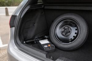 Roue de secours, cric et kit anti-crevaison dans le coffre d’une voiture